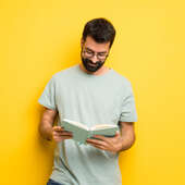 Mann mit Bart und grünem Hemd liest in einem Buch